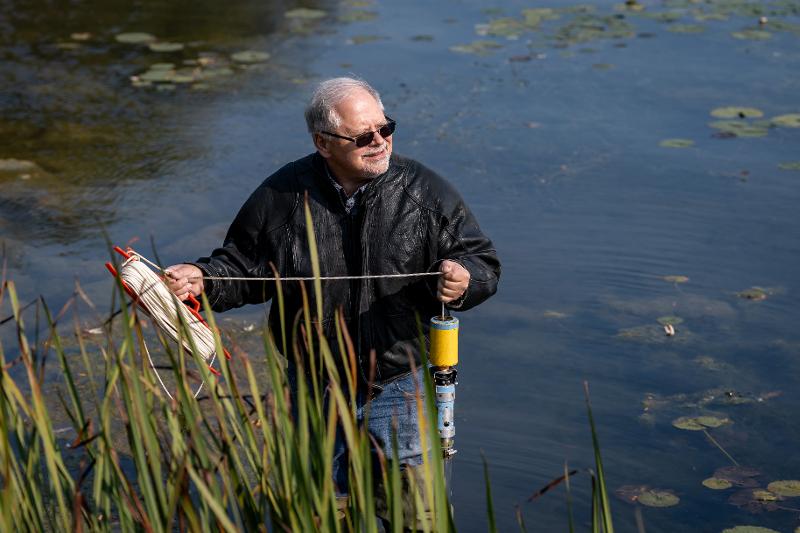 a man standing in water with sampling equipment